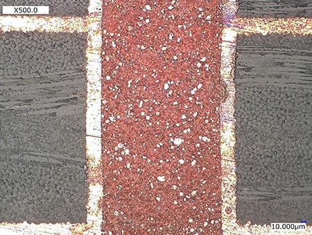 Observación de áreas decoloradas en una sección transversal de una PCB (500x)